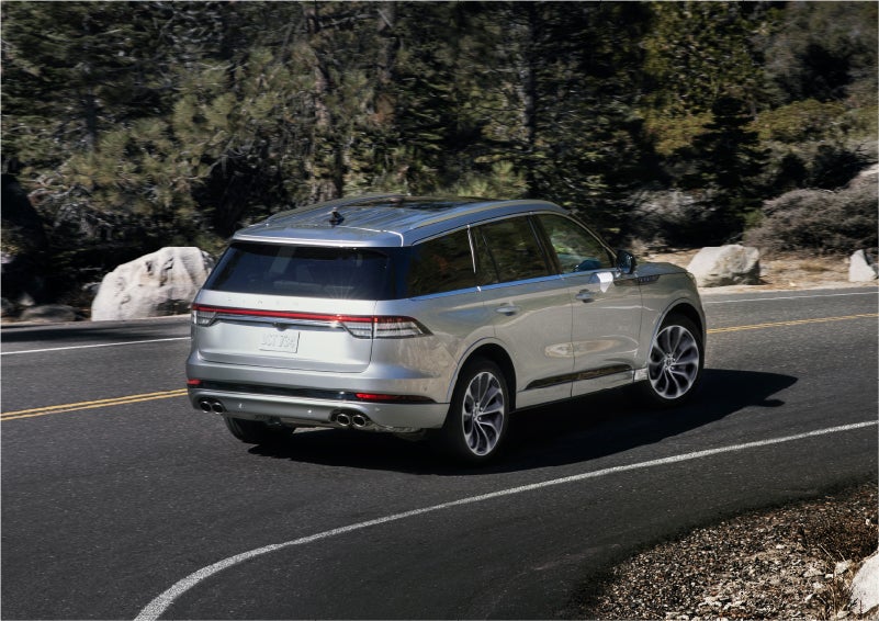 A 2023 Lincoln Aviator® Grand Touring model is shown being driven on a tight turn of a mountain road | Rogers Lincoln in Midland TX