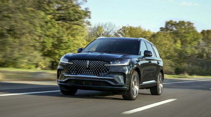 A 2025 Lincoln Black Label Aviator® SUV is being driven down a road lined with trees. | Rogers Lincoln in Midland TX