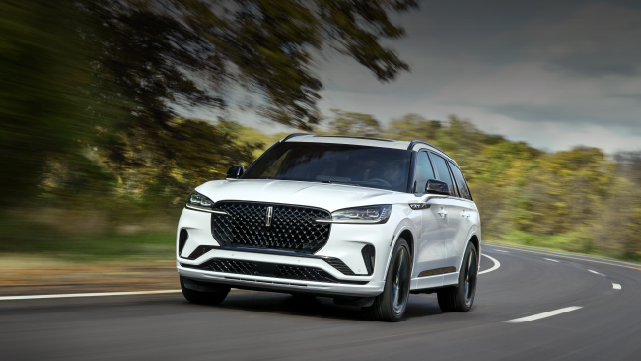 A white 2025 Lincoln Aviator® SUV is being driven down a road lined with trees. | Rogers Lincoln in Midland TX