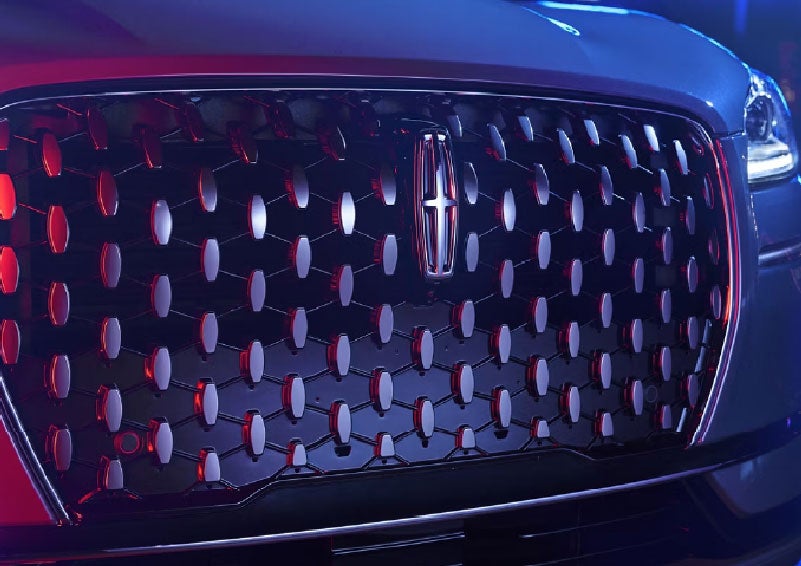 The grille of a 2025 Lincoln Corsair® SUV reflects neon light at night. | Rogers Lincoln in Midland TX