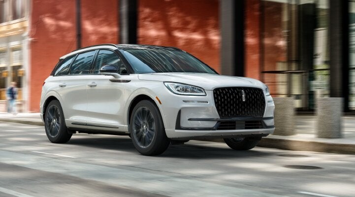 A white 2025 Lincoln Corsair® SUV with the Jet Appearance Package is being driven through a city.| Rogers Lincoln in Midland TX