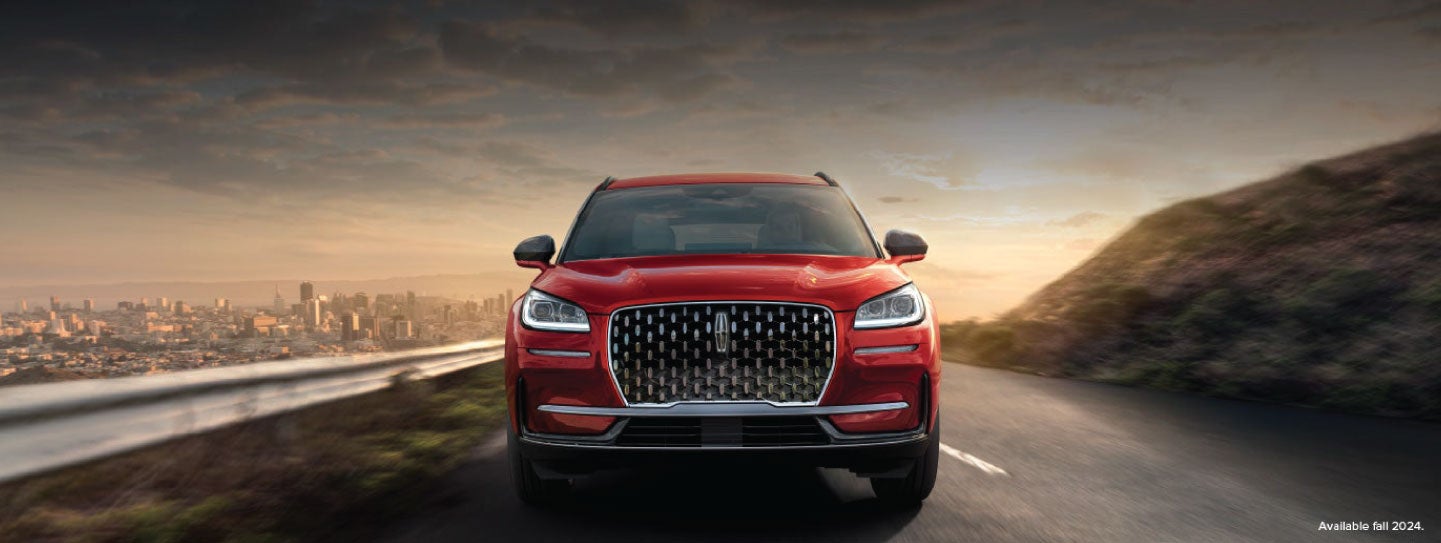 A 2025 red Lincoln Corsair® SUV is being driven down a road at sunset. | Rogers Lincoln in Midland TX