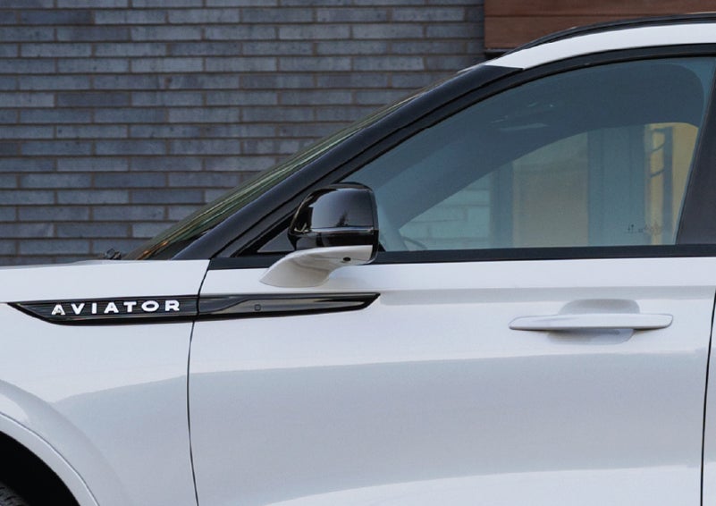 The driver’s side door and fender badging of a white 2026 Lincoln Aviator® SUV are showcased. | Rogers Lincoln in Midland TX