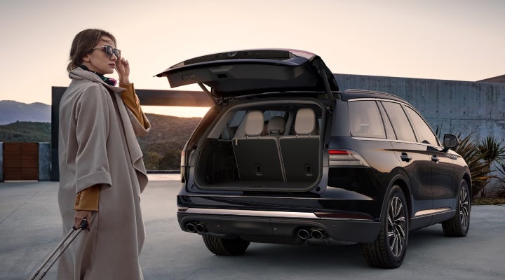 A woman approaches a 2026 Lincoln Aviator® SUV with its rear liftgate open. | Rogers Lincoln in Midland TX