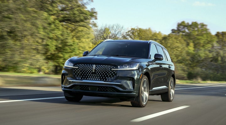 A 2026 Lincoln Black Label™ Aviator® SUV is being driven down a road lined with trees. | Rogers Lincoln in Midland TX