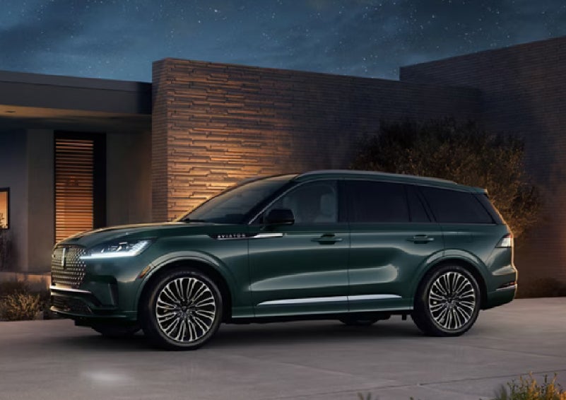 A green 2027 Lincoln Aviator® SUV is parked outside a contemporary home. | Rogers Lincoln in Midland TX