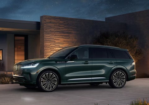 A green 2027 Lincoln Aviator® SUV is parked outside a contemporary home. | Rogers Lincoln in Midland TX
