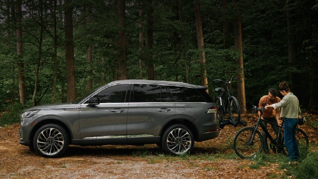 A father and son load e-bikes on a bike rack attached to a 2027 Lincoln Aviator® SUV. | Rogers Lincoln in Midland TX